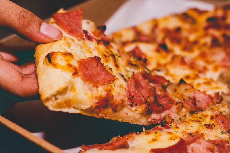 A close-up photo of a person holding a slice of pizza
